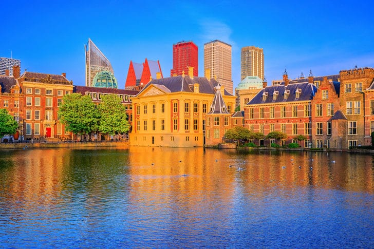 Older buildings in The Hague with skyscrapers in the background, water in the foreground