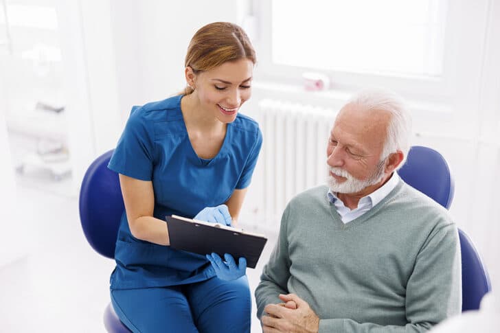 A doctor asking a senior citizen to sign a form to consent before performing a procedure.