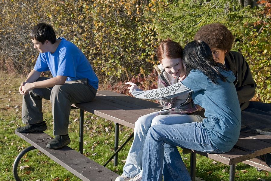 Picture of three teens sitting together and another teen sitting to the site, left out