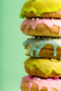 Picture of a stack of donuts in various colors including yellow, pink, and green.