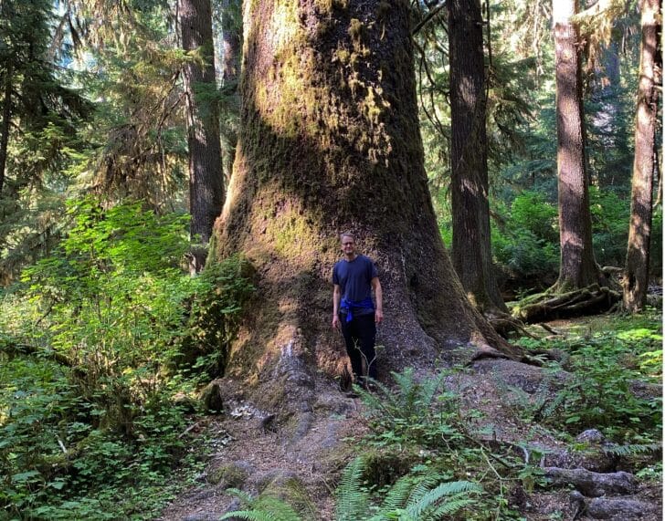 Picture of Andrew Allemann at the Hoh Rainforest standing in front of a tree