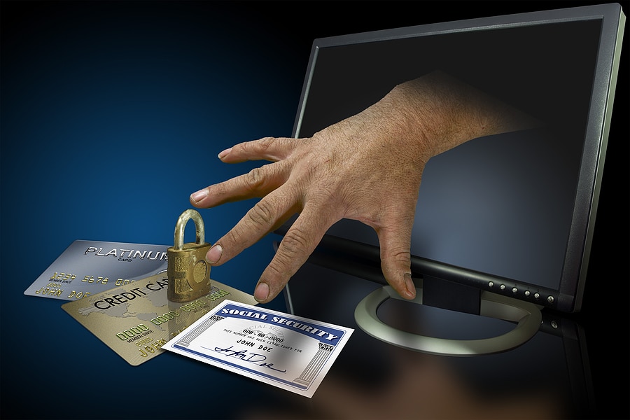 picture of hand reaching out from a computer monitor to grab credit cards and a social security card