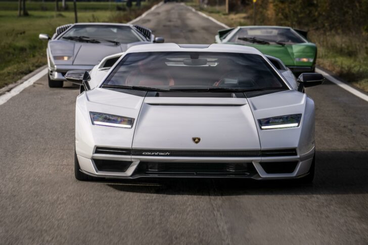 Photo of three Lamborghini cars.  A white is in front with a gray in the rear left and a green car in the rear right.