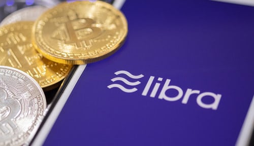 Picture of mobile phone with Facebook Libra cryptocurrency logo and representations of bitcoin
