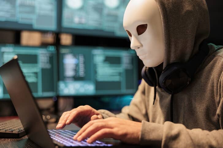 Masked thief at computer