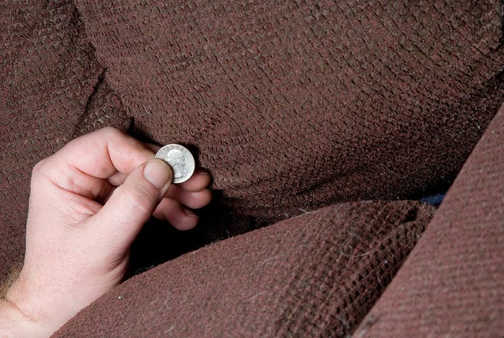Picture of hand holding a quarter found in a brown couch cushion.