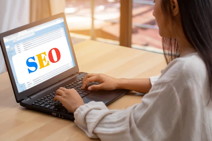 A woman in front of a keyboard with a page that says SEO