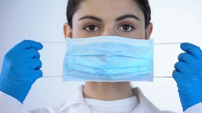 Picture of woman doctor wearing surgical gloves and putting on a surgical mask