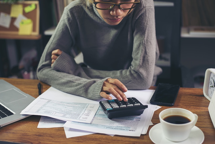 Picture of a women with a calculator calculating her taxes