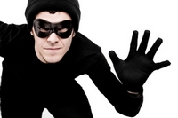 Picture of robber in black clothing, black at, black gloves and eye mask