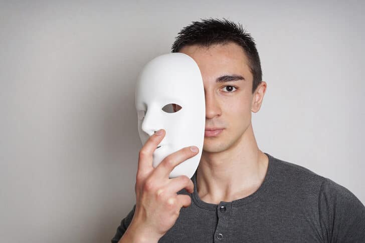 Man removing a mask to reveal his identity