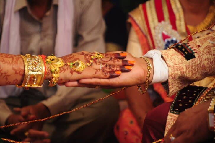  hand of the bride held by a groom during a Indian traditional ritual in an Indian Hindu Wedding